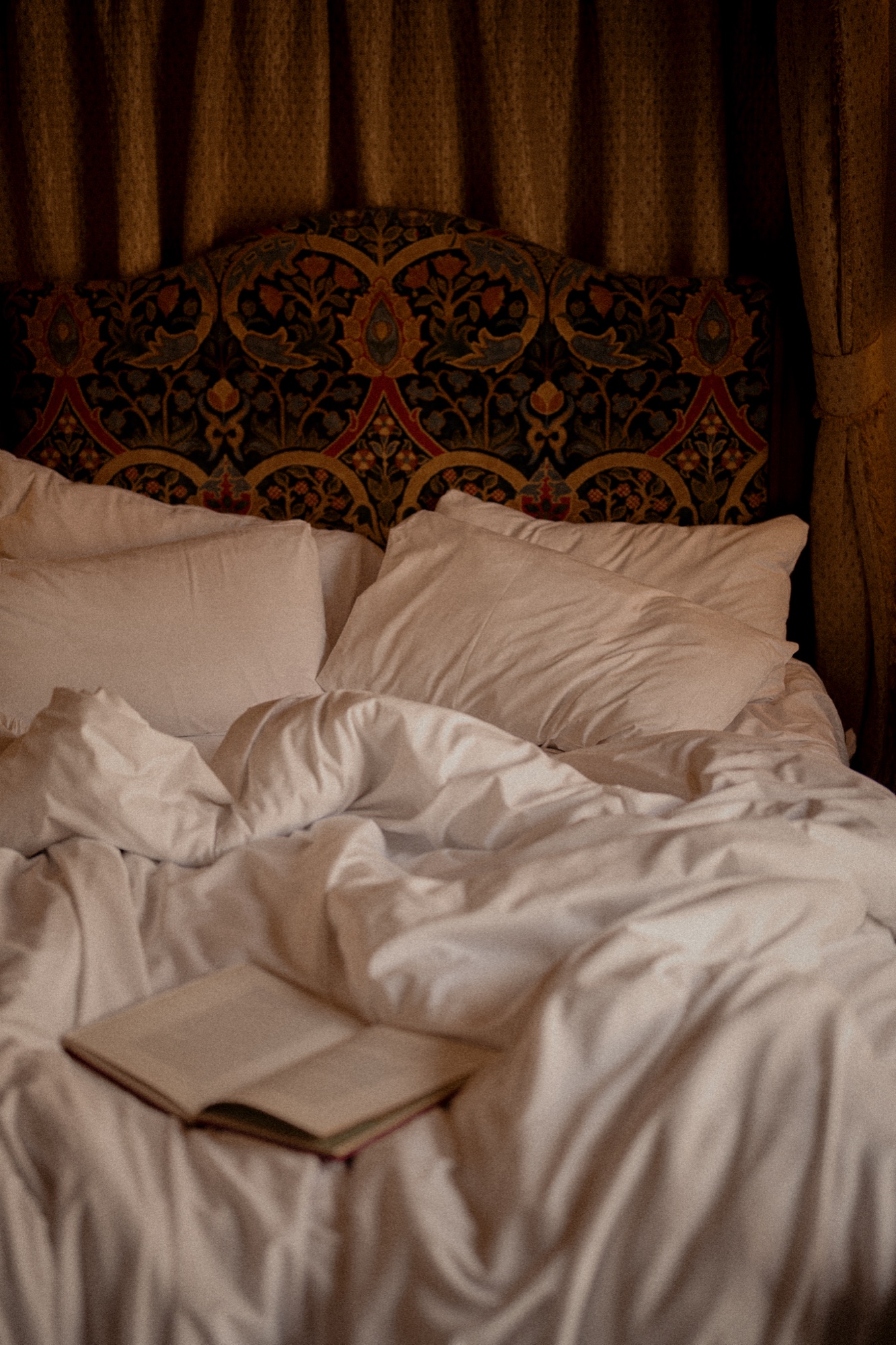 A neatly dressed bed and upholstered headboard in a guest room at The Red Lion.