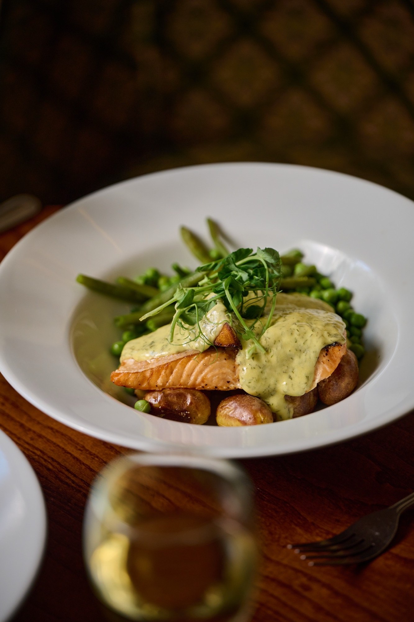 A salmon main course plated simply on a ceramic plate at The Red Lion, warm daylight.