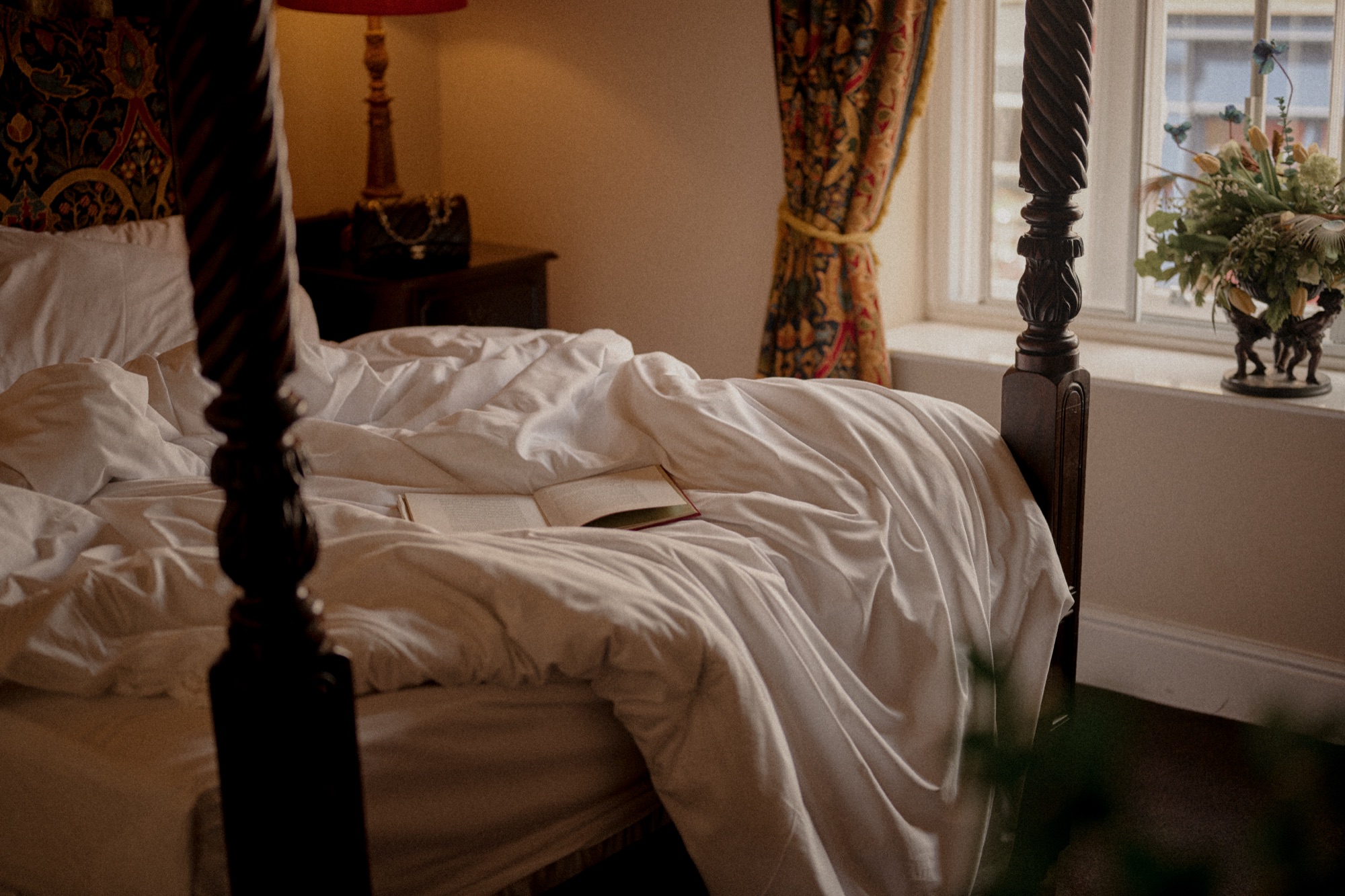 A guest bed beside a window at The Red Lion with daylight falling across white linen.