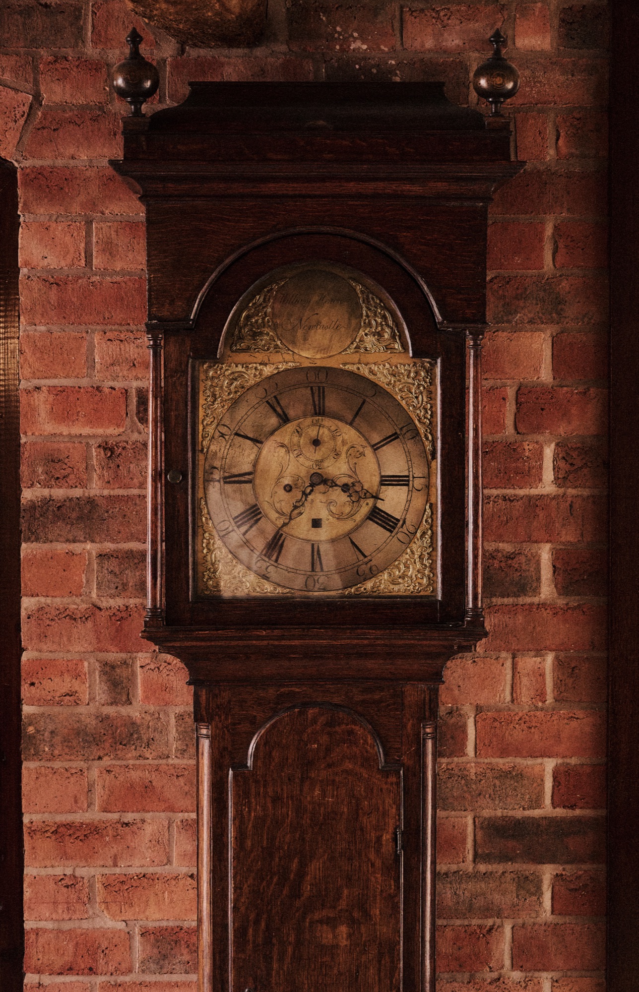 An antique long-case clock against an exposed brick wall at The Red Lion.