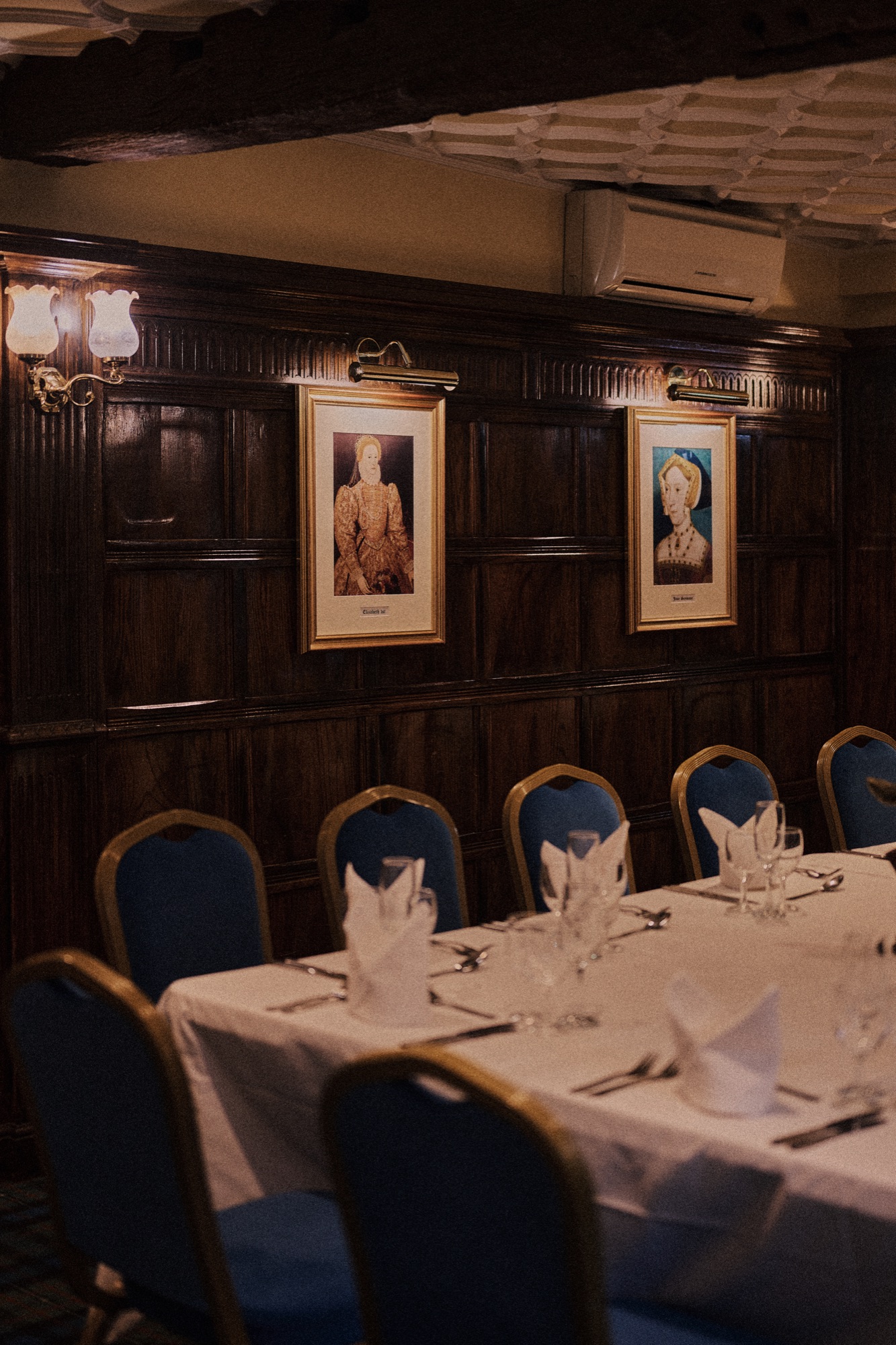 The private dining room at The Red Lion, tables set with white linen under wood panelling and framed portraits.