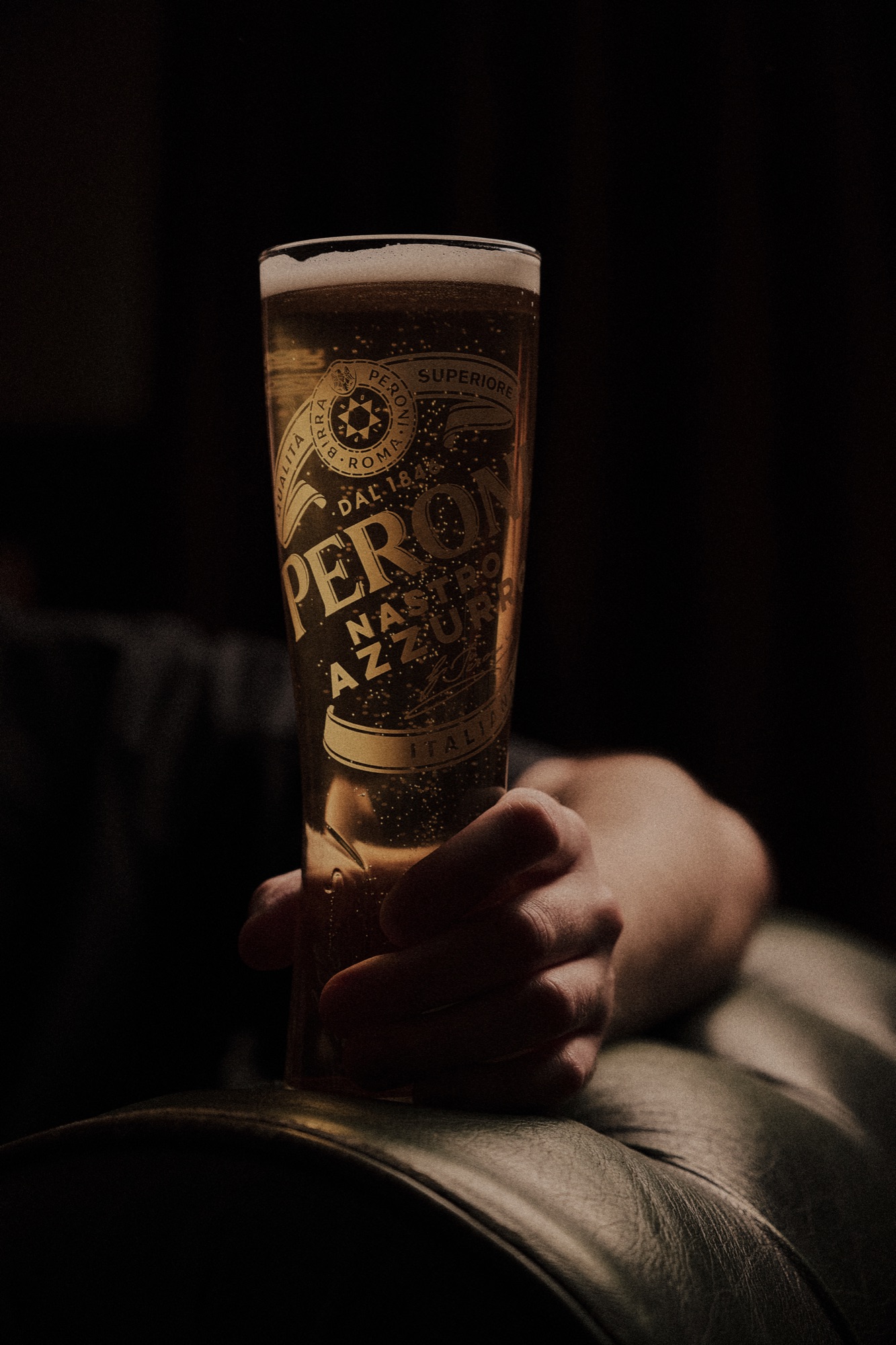 A cold lager held in low light at The Red Lion, condensation on the glass.