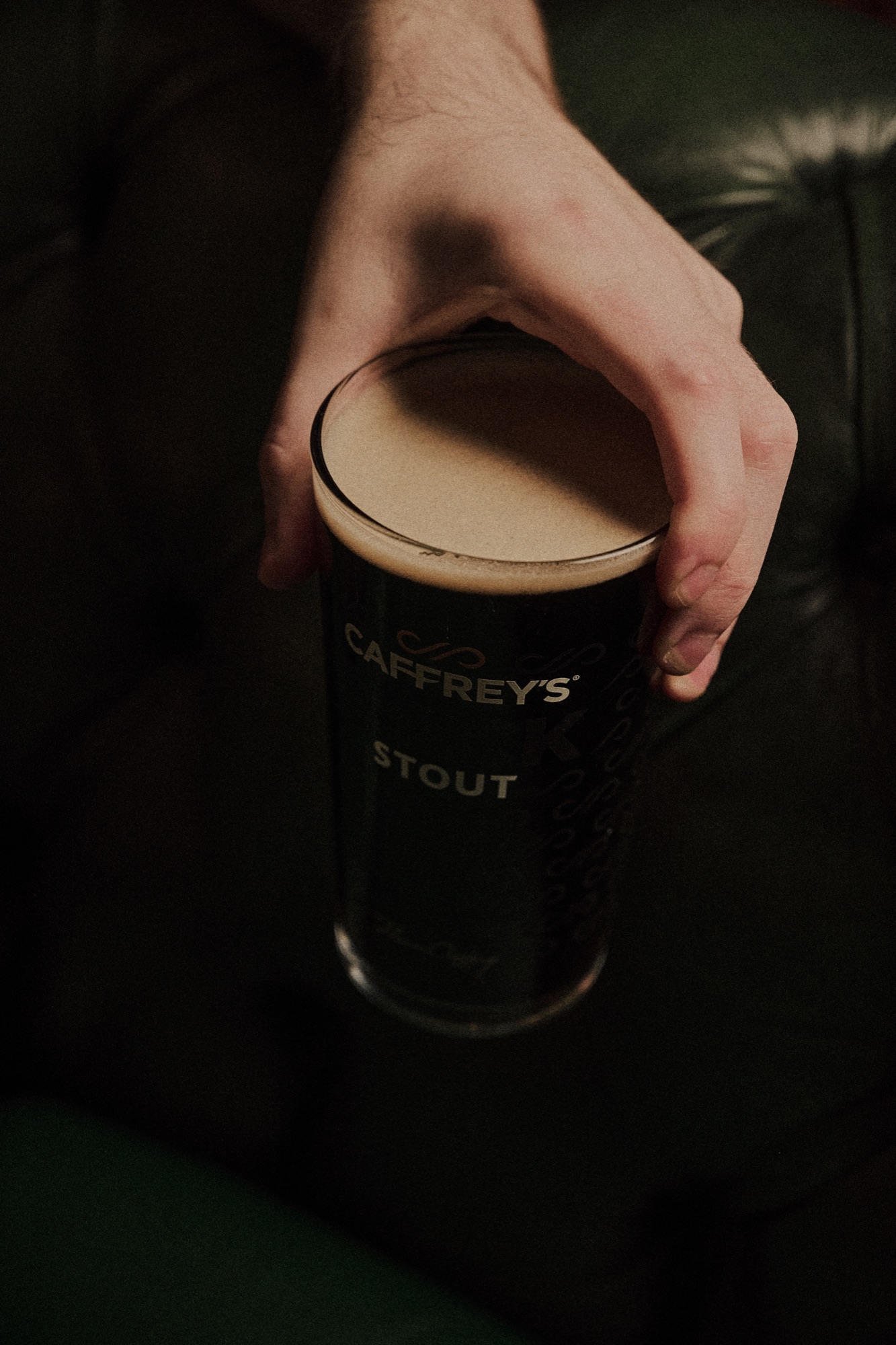 A hand holding a settling pint of stout at The Red Lion, warm dark tones.